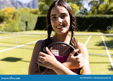 Portrait Of Smiling Biracial Young Woman Holding Tennis Racket While