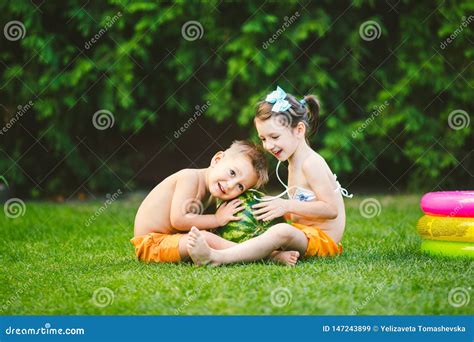 Two Children Caucasian Brother And Sister Sitting On Green Grass In