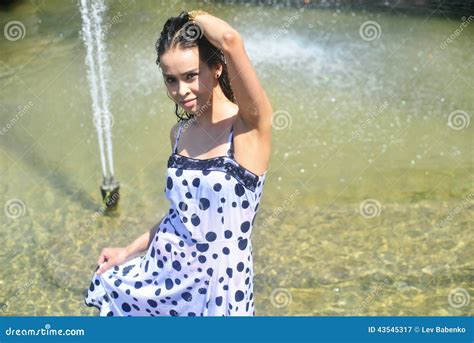 Lächelndes Mädchen In Einem Nassen Kleid Und Machte Das Haar Nass Das Im Wasser Am Brunnen