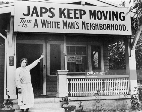 A Photograph Of A White Female Pointing At A Sign Above Her House