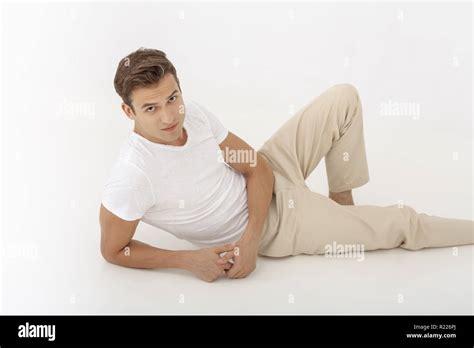 Young Casual Man Looking Pensive While Lying Down On White Background