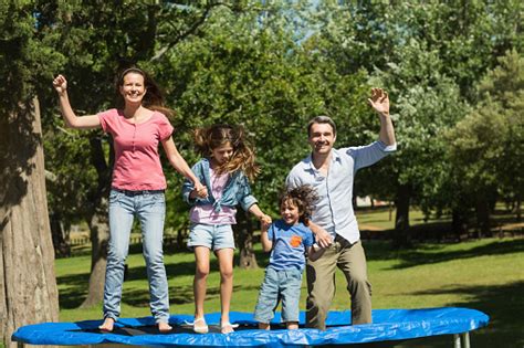 Stand in middle of trampoline with feet slightly wider than hips distance. Happy Family Jumping High On Trampoline In Park Stock ...