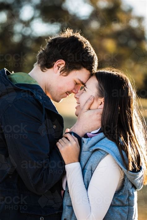 Image Of Young Couple Standing Close Together Foreheads Touching Him Touching Her Face Smiling