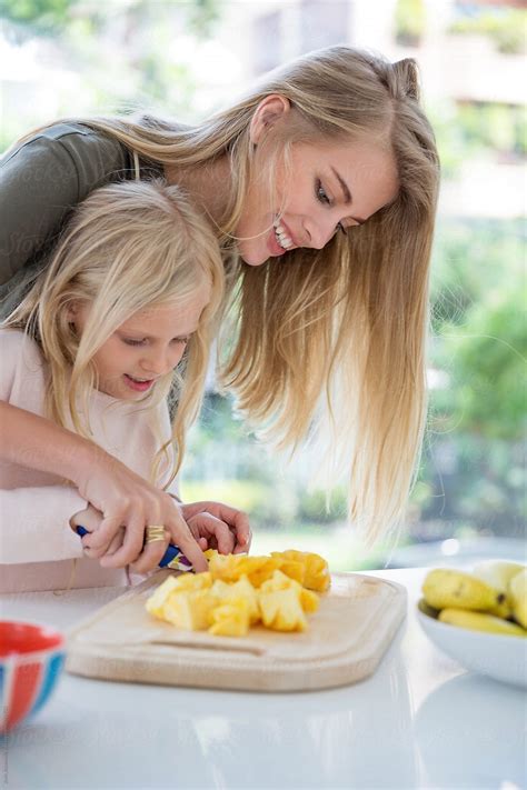 Smiling Mother And Daughter Cutting Pineapple Del Colaborador De
