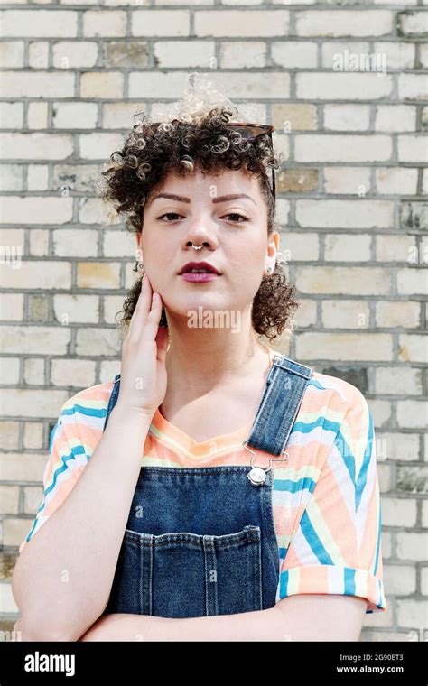 Young Woman Touching Cheek In Front Of Brick Wall Stock Photo Alamy
