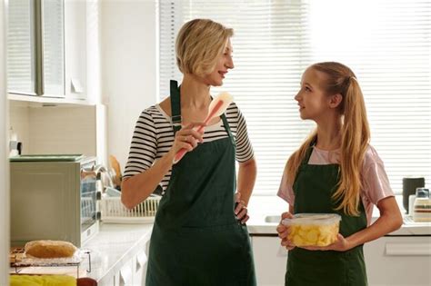 Premium Photo Smiling Mother Teaching Her Preteen Daughter Cooking