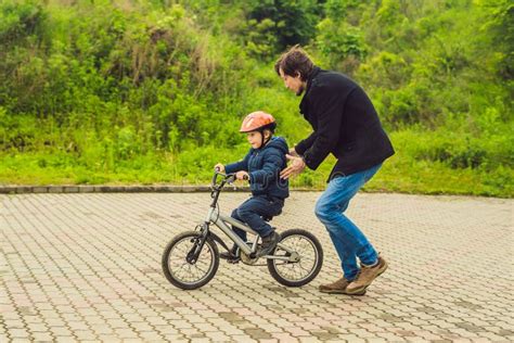 Dad Teaches Son To Ride A Bike In The Park Stock Photo Image Of
