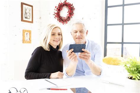 Happy Senior Couple Using Mobile Phone And Making Video Call At Home