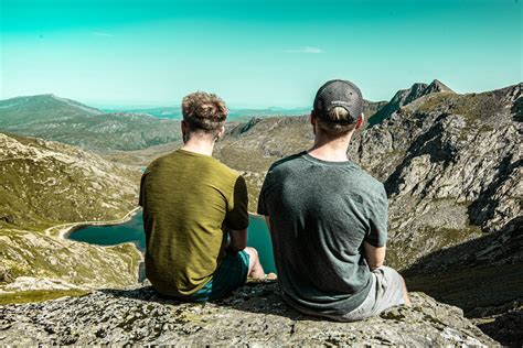 Two Men Sitting On Cliff During Daytime Photo Free Nature Image On