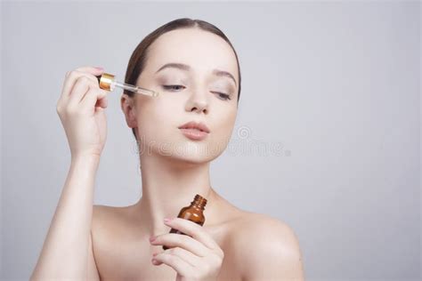 Close Up Of Pretty Brunette Lady Applying Cosmetic Oil On Her Face With