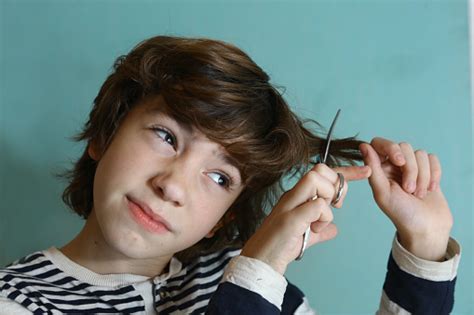 The hair is brushed on all sides with some hanging down over the forehead and some covering the tip of. Teenager Boy Cut His Hair With Scissors Stock Photo ...