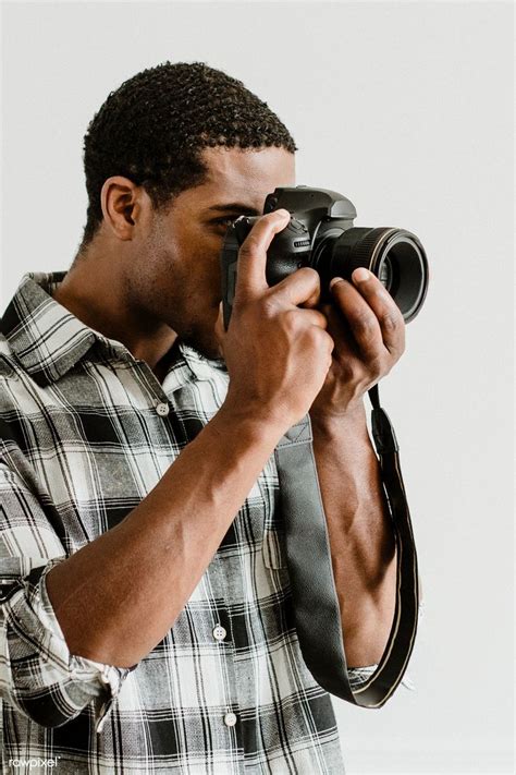 A Man Holding A Camera Up To His Face And Taking A Photo With Its Lens