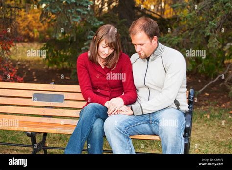 Young Married Couple Praying Together On A Park Bench Edmonton