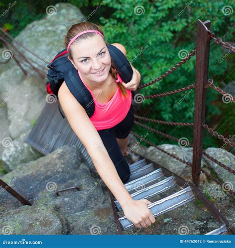 Beautiful Young Woman Climbing A Ladder In Naturalnational Park Stock