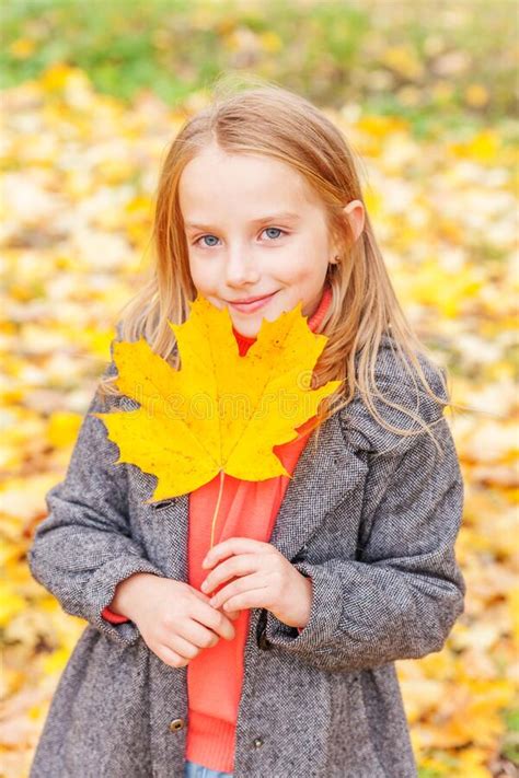 Happy Young Girl Playing With Falling Yellow Leaves In Beautiful Autumn