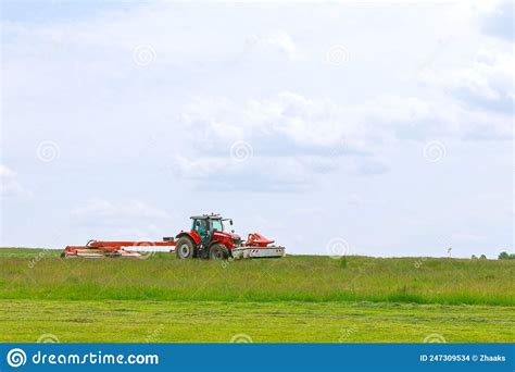 A Red Tractor Mows The Grass On A Farmer S Field Two Mowers Will Mow A