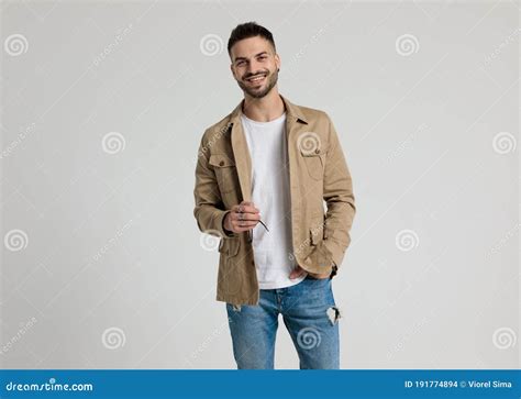 Happy Young Casual Guy In Jacket Holding Hand In Pocket Stock Photo