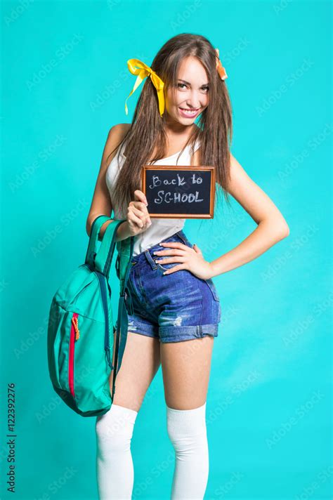 Sexy Young Girl School Girl In Denim Shorts And White T Shirt With A Backpack On A Blue
