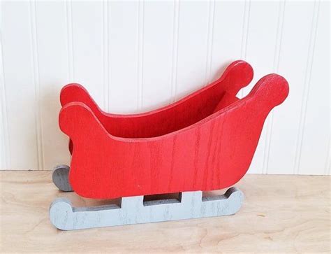 A Red Sleigh Sitting On Top Of A Wooden Table Next To A White Wall