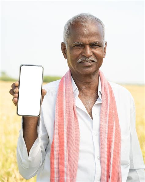 Smiling Old Indian Farmer Standing In Front Of Farmland By Holding