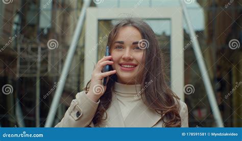 Happy Young Woman Talking On The Cell Phone While Walking Near Big