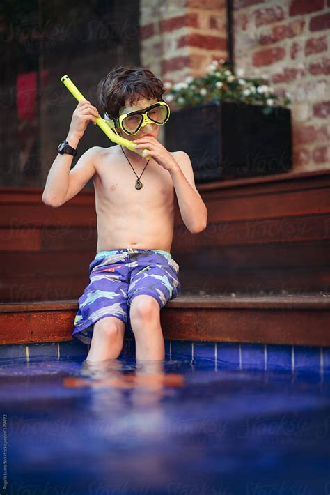 Boy With Snorkel Set Sitting On The Side Of A Pool Del Colaborador De