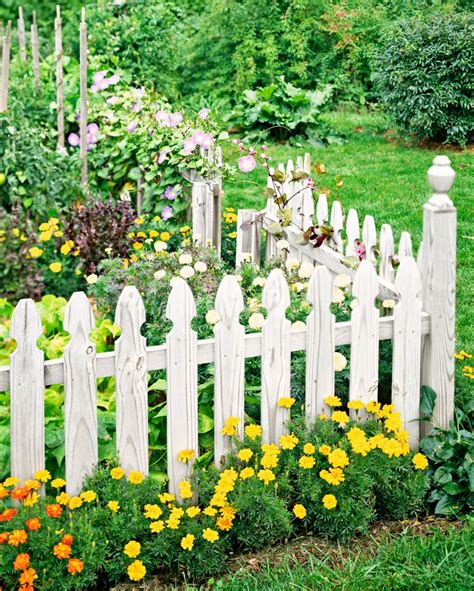 A White Picket Fence Surrounded By Flowers And Greenery