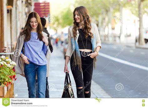 Two Beautiful Young Women Walking And Talking In The Street Stock