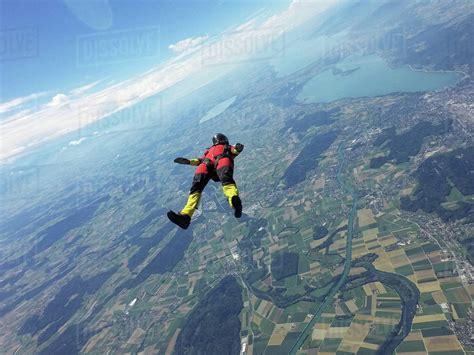 Female skydiver free falling on back above landscape - Stock Photo 