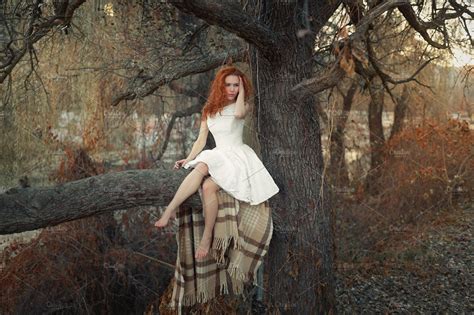Young Girl Is Sitting On A Tree In A Forest High Quality People