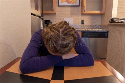 Young Woman Cries And Buries Her Head And Face In Her Arms While