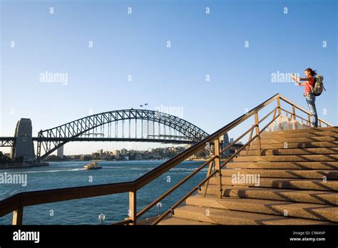 A Backpacker Photographs The Sydney Harbour Bridge From The Steps Of