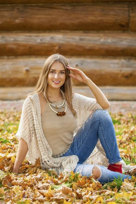 Happy Beautiful Woman In Blue Jeans Sitting In The Autumn Park Stock