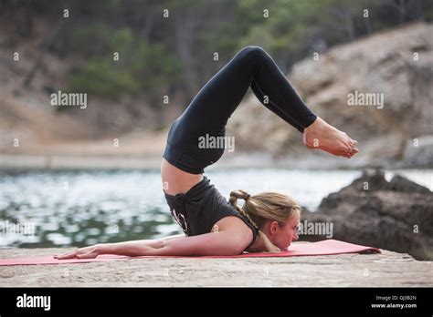 Young Woman Bending Over Backwards Practicing Yoga Position On Sea Pier