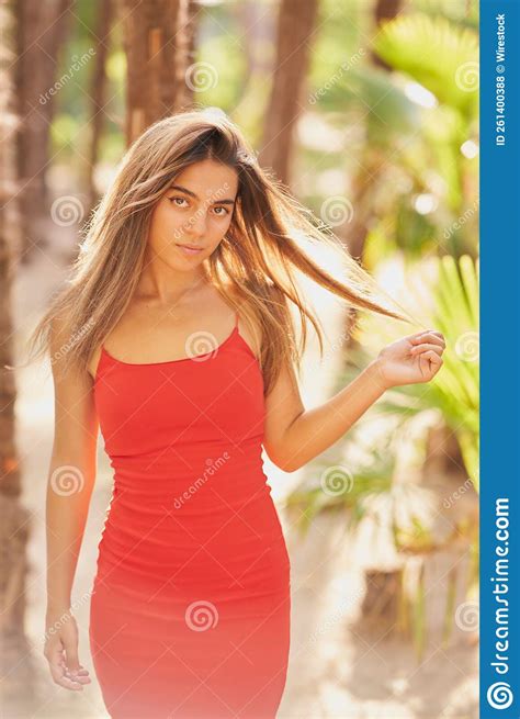 Girl With Tight Red Dress And Long Straight Hair Posing In A Park Stock