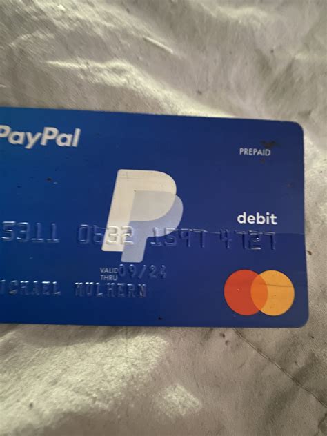 a blue paypal credit card sitting on top of a white bed sheet with the