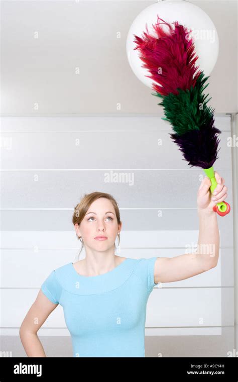 Young Woman Dusting Lamp With Feather Duster Stock Photo Alamy