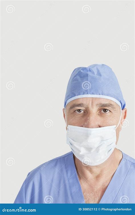 Portrait Of Senior Surgeon With Surgical Cap And Mask Over Gray