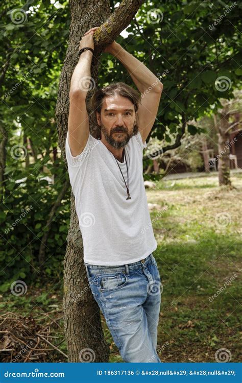 Handsome Man Leaning On A Tree And Holding A Branch In The Outside Park