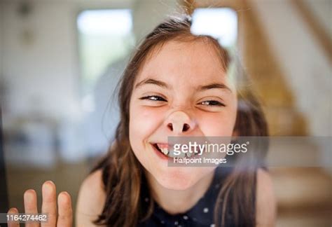 Front View Portrait Of Small Girl Pressing Nose Against Glass Window