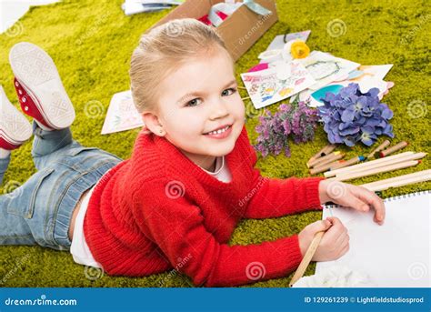 Smiling Little Child Drawing With Color Pencils On Green Stock Image