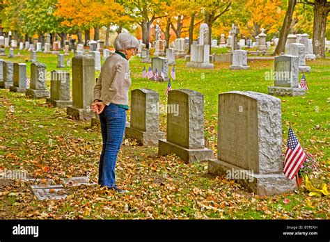 A Woman Visits Her Parents Grave In A Cemetery On An Autumn Afternoon