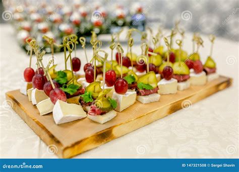 The Buffet At The Reception Assortment Of Canapes On Wooden Board