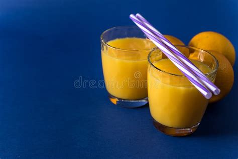 Glass Of Fresh Juice And Orange On A Classic Trendy Blue Background
