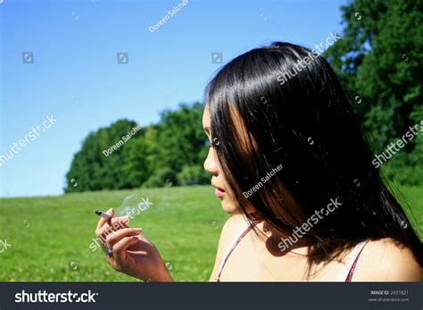 A Young Asian Woman With Black Hair Is Smoking A Cigarette And Sit On