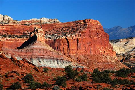 Panorama of red rocks and american flag waving on a beautiful summer day with blue sky. Capitol Reef National Park, Utah, USA - Traveldigg.com