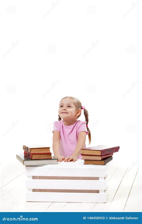 Joyful Little Girl With Books Sits On A White Floor Stock Image