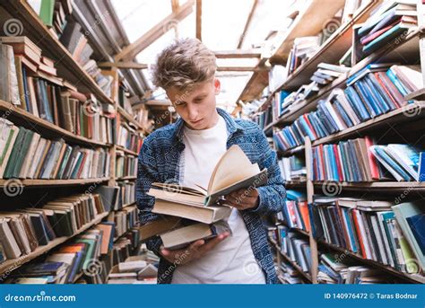 Handsome Young Man Stands In An Old Public Library With Books In His