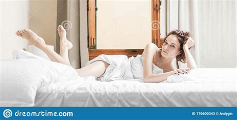 Charming Girl Lies In Bed She Stretched Out Her Legs And Looks