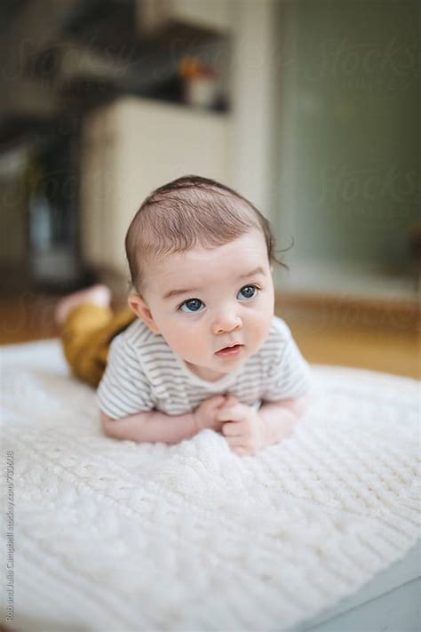 Cute Young Baby Lying On Blanket On Floor By Rob And Julia Campbell